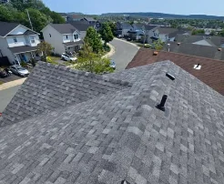 Grey shingled roof with houses and a hillside neighbourhood below